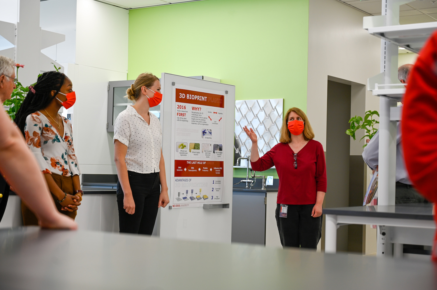 Researchers point to a poster explaining 3D Bioprinting in a lab at the Plant Sciences Building.