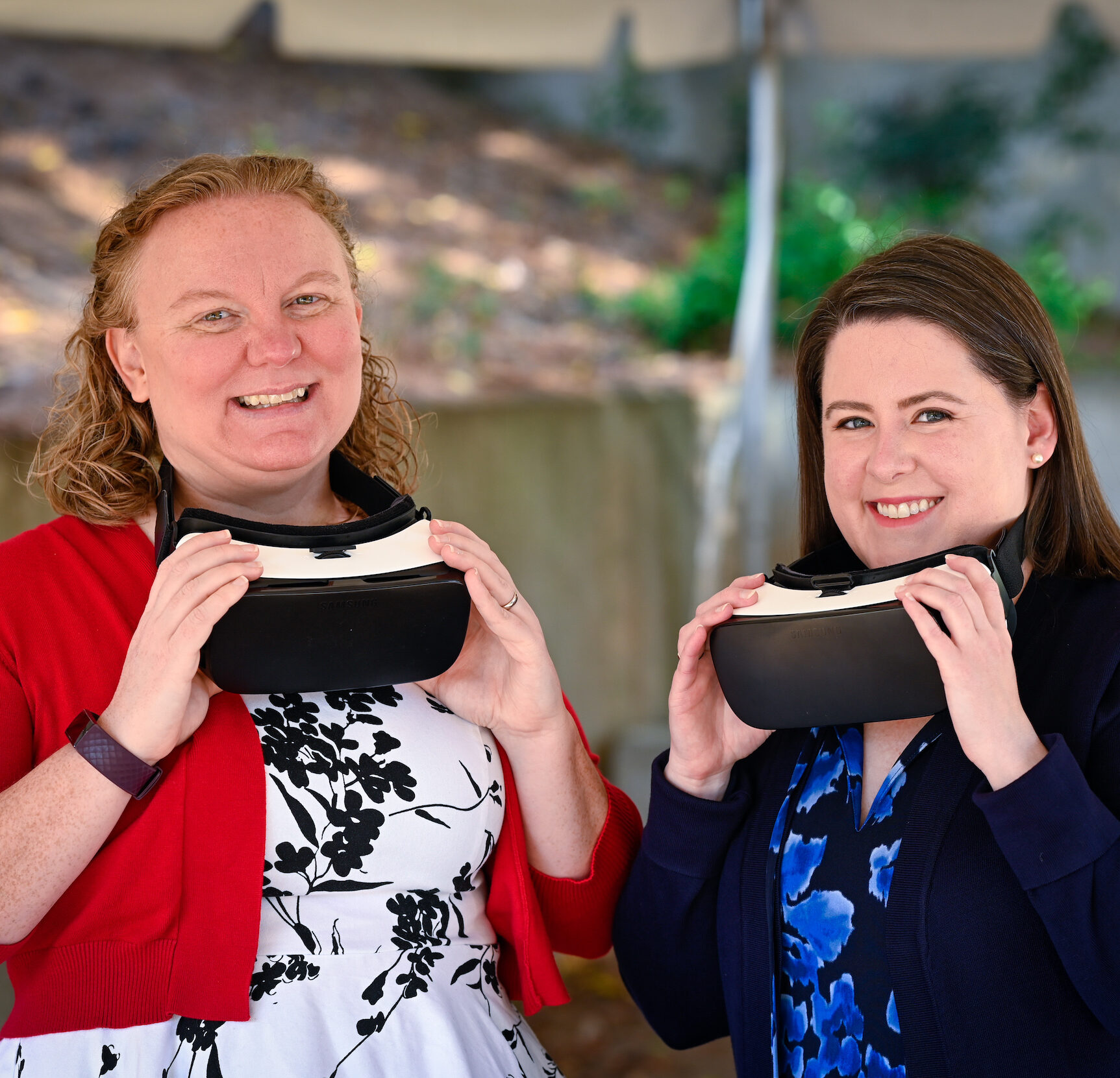 two women hold up virtual reality goggles