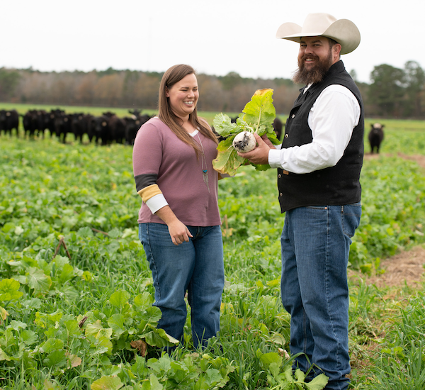 two people stand in a pasture