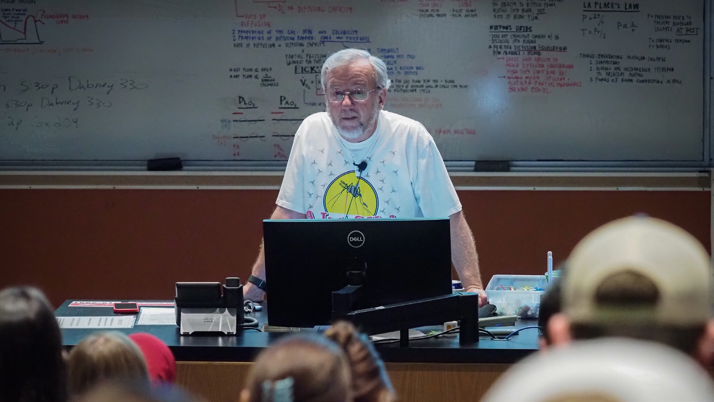 Clyde Sorenson stands behind a computer screen at the front of the class