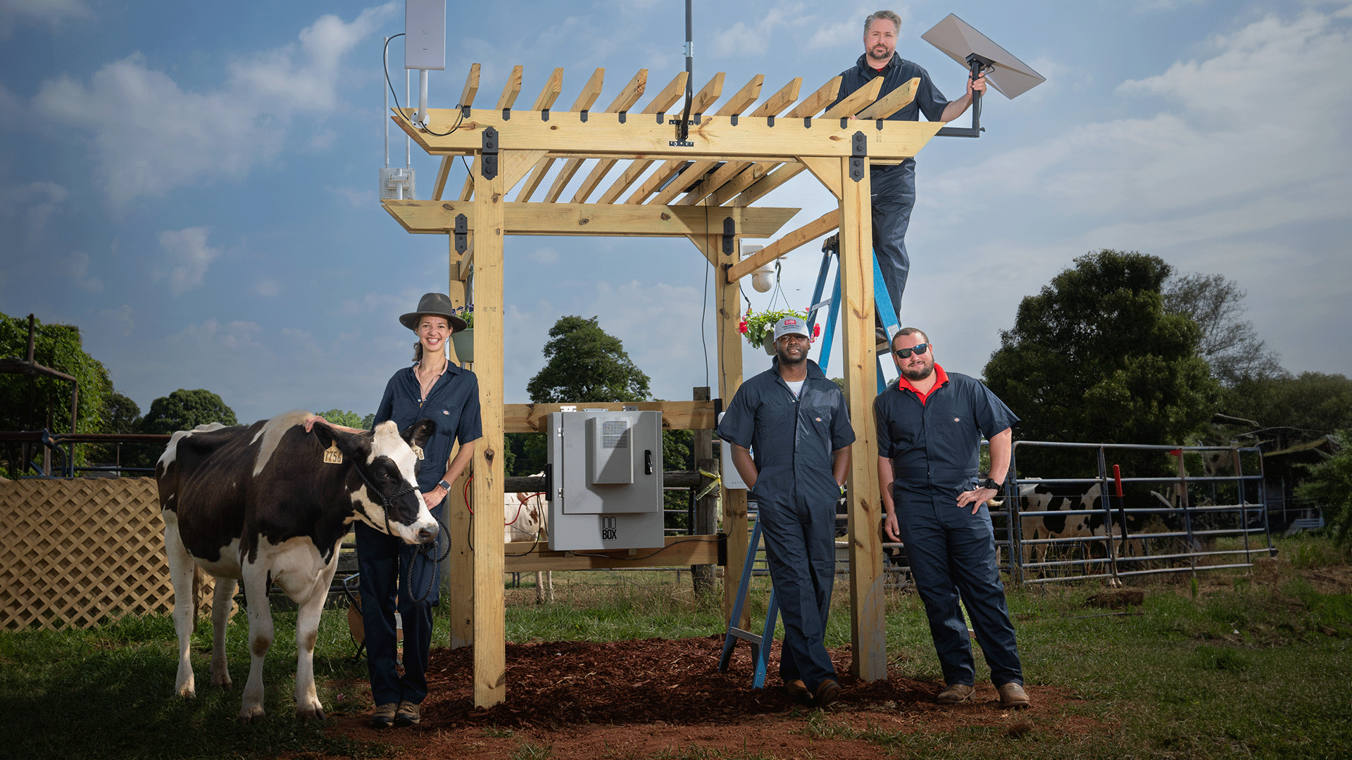 people standing around tech equipment on a farm with a cow