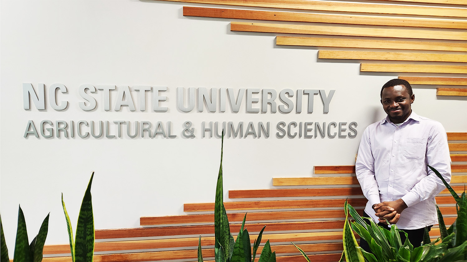 Joseph Gakpo standing in front of the NC State Agricultural and Human Sciences sign