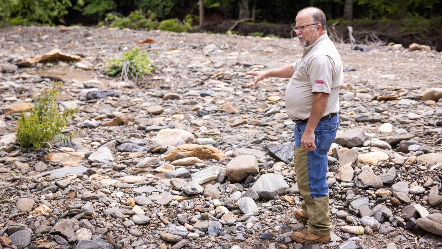 former farm covered in rocks and a man pointing at the ground