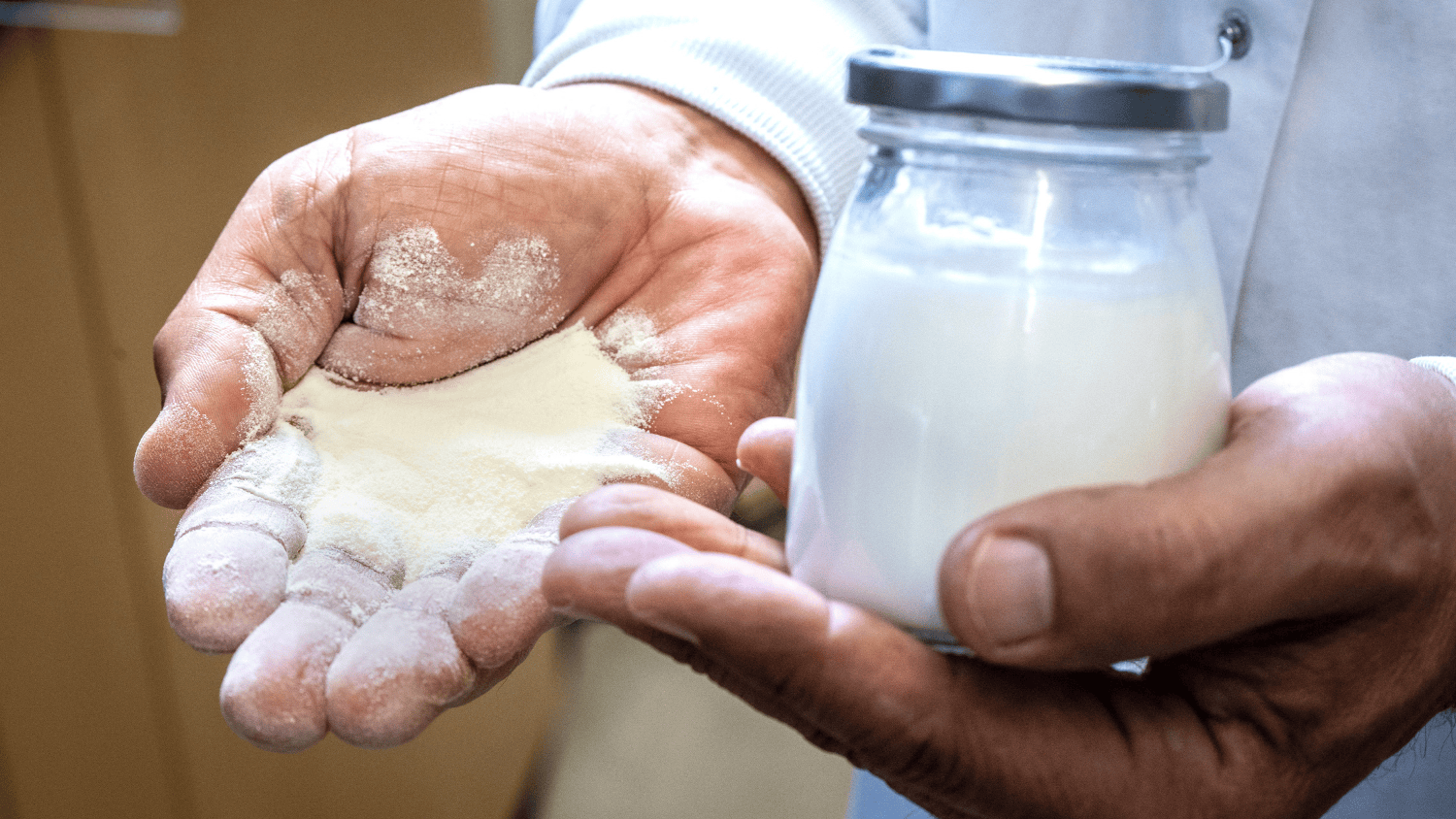 one hand holding a powder and the other holding a yogurt
